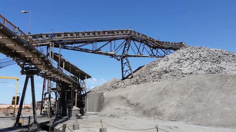 Collapsed stacker resting on stockpile and showing product build-up on bottom chord.